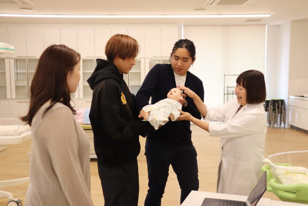 高専の学生が赤ちゃんを抱えてみる写真